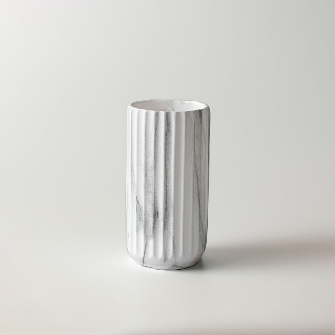 White marble texture ceramic cylinder vase with vertical ribbed fluting on a white background for modern interior styling.