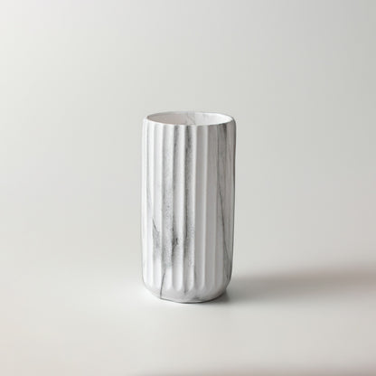 White marble texture ceramic cylinder vase with vertical ribbed fluting on a white background for modern interior styling.