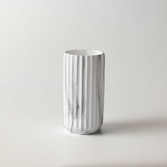 White marble texture ceramic cylinder vase with vertical ribbed fluting on a white background for modern interior styling.