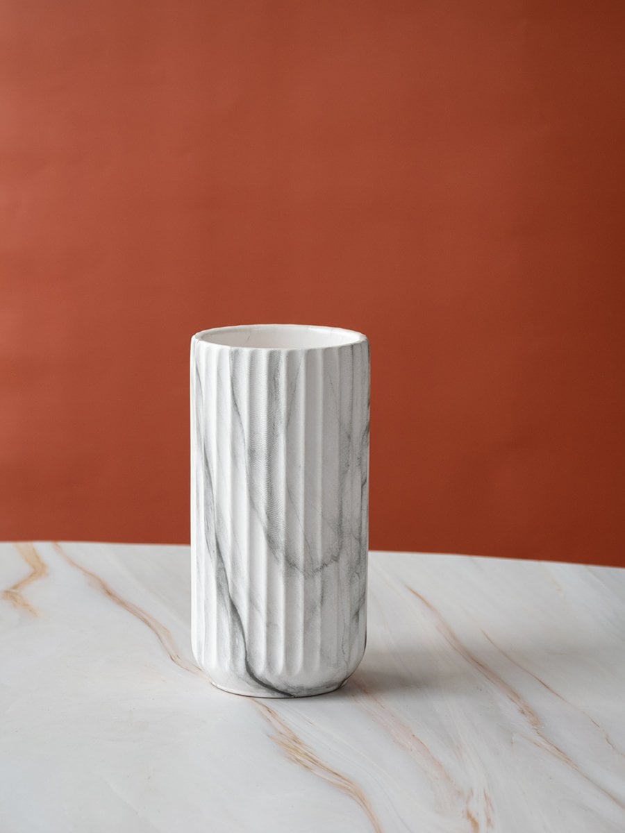 A clean white background showcasing a marble textured cylindrical vase with soft grey veining and smooth vertical grooves for a modern minimal look.