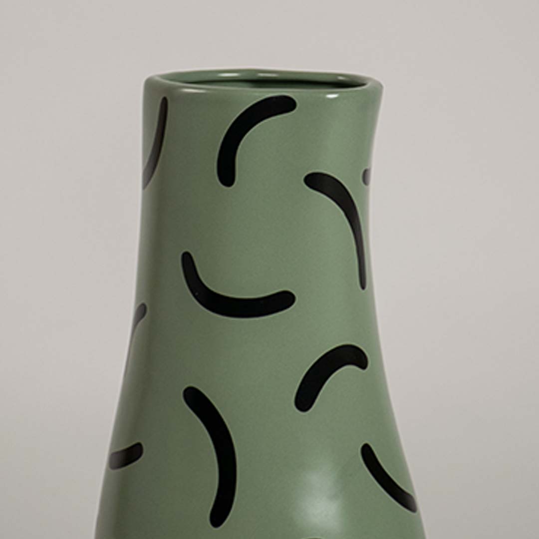 Closeup of green ceramic vase with bold black curved pattern showcasing its smooth finish and modern decorative detailing.