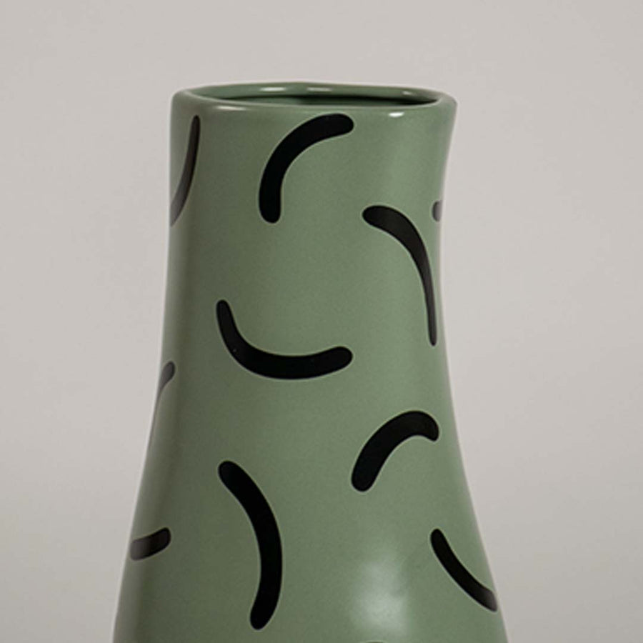 Closeup of green ceramic vase with bold black curved pattern showcasing its smooth finish and modern decorative detailing.