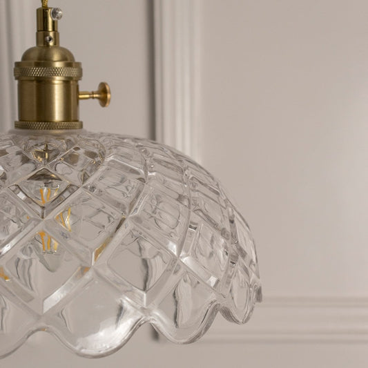 Closeup of clear patterned glass pendant light with gold metal details showcasing premium craftsmanship.
