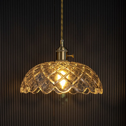 Crystal glass pendant light with golden glow against dark background highlighting intricate diamond cut glass pattern.