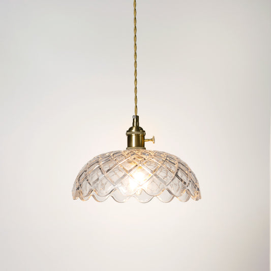 Illuminated clear glass pendant light with gold chain creating soft ambient lighting for homes.