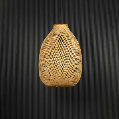 Rattan pendant light with tall handwoven bamboo shade in natural finish turned off against black background.