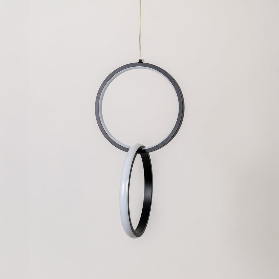 Modern metal dual ring hanging light in black and white shown switched off on white background for minimal wall decor.