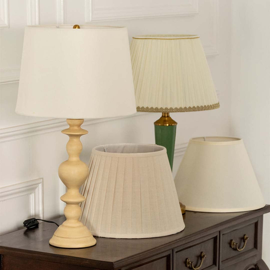 White rectangular shade marble and gold geometric table lamp on wooden sideboard with light off for contemporary elegant décor.