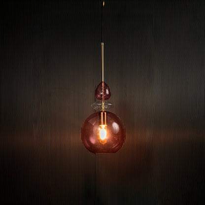 Light off decorative rose pink hanging light with gold accents mounted on a dark ceiling.