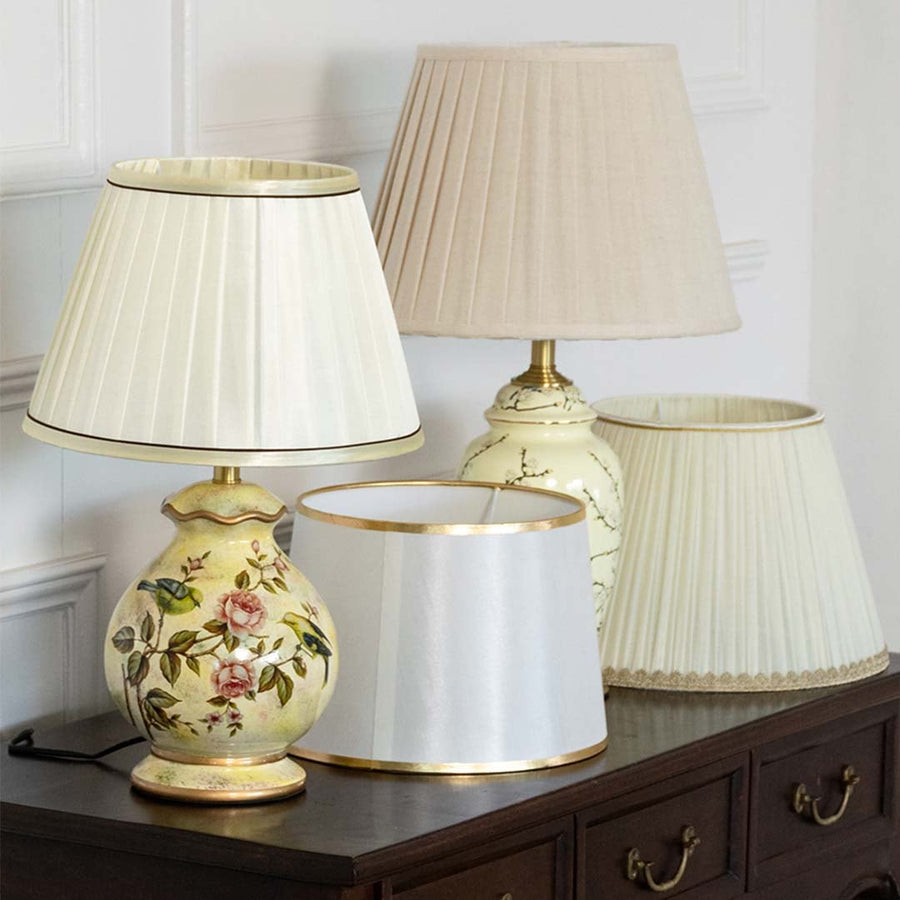 Table lamps light off with floral patterned bases and pleated white shades placed on a wooden console for classic decor styling.
