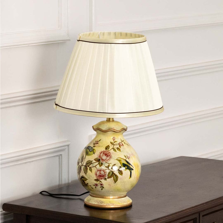 Unlit floral ceramic lamp with gold base and white pleated shade highlights its graceful silhouette and exquisite painted craftsmanship.