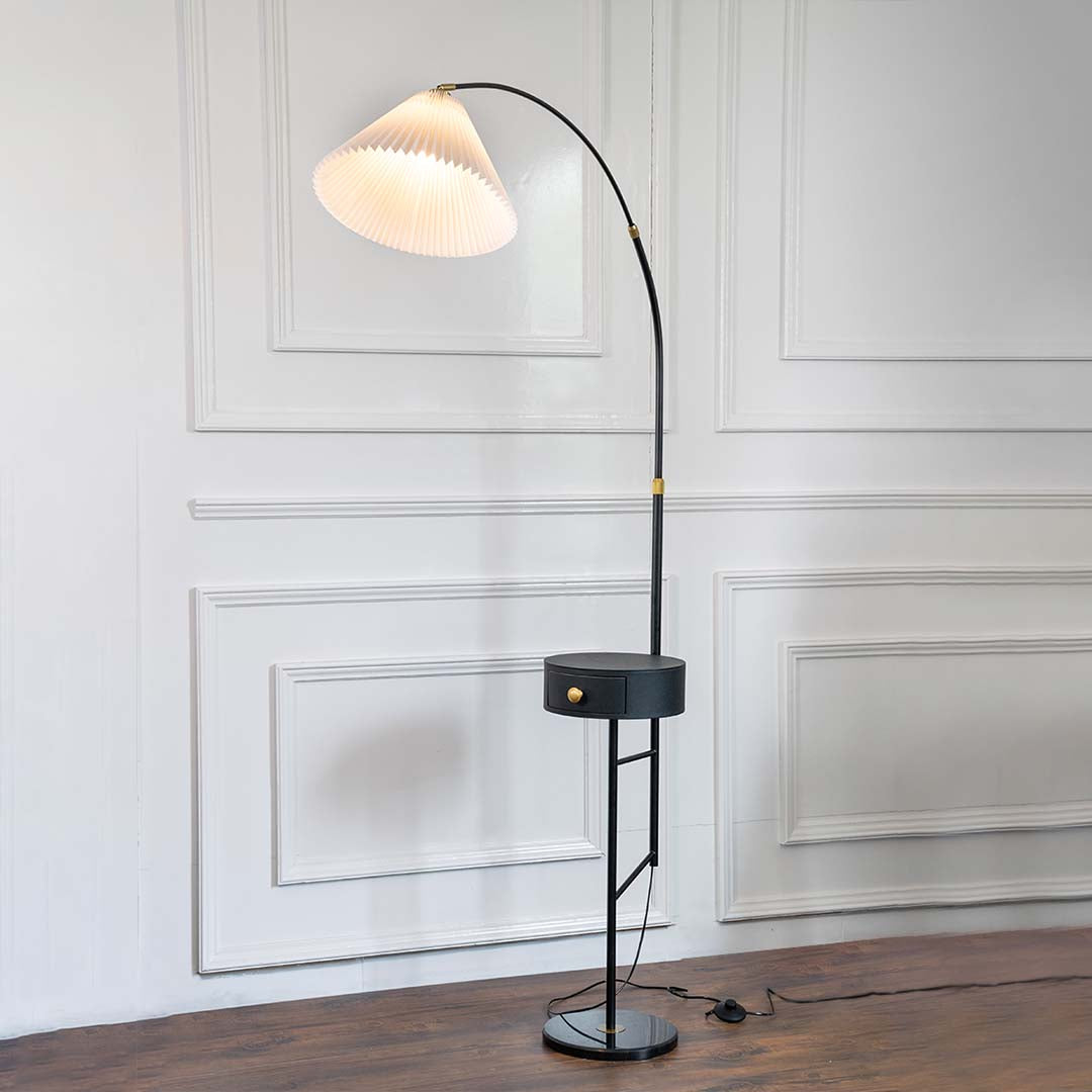 Black metal floor lamp with sculptural white shade and brass stem for modern living room and reading nook decor.