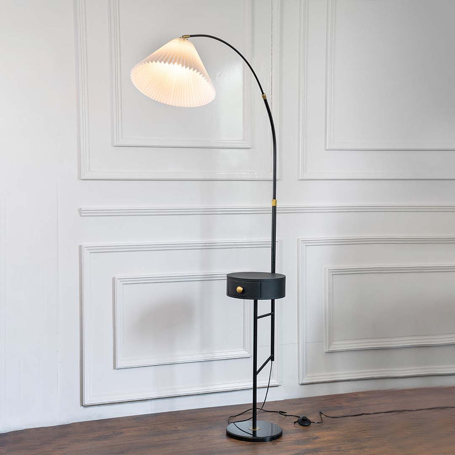 Black metal floor lamp with sculptural white shade and brass stem for modern living room and reading nook decor.