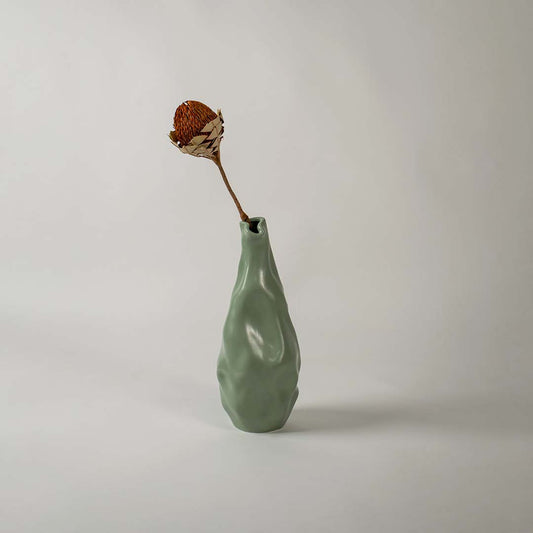 A modern green sculpted vase displayed in a soft lifestyle setting showing its unique organic shape and smooth artistic texture that enhances any contemporary decor.