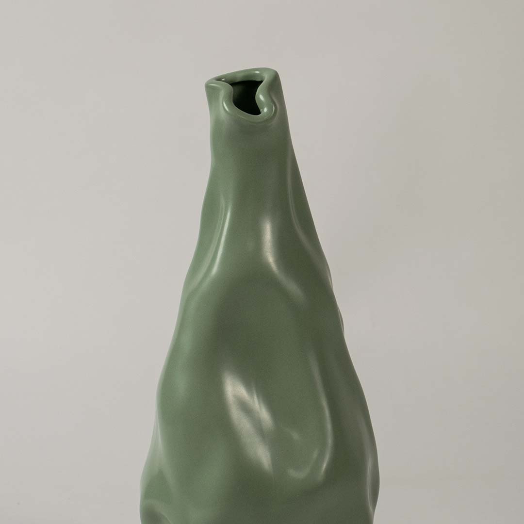 Closeup view of the green sculpted vase showing its smooth artistic contours and fluid handcrafted detailing that create a striking modern decorative accent for interiors.