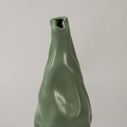 Closeup view of the green sculpted vase showing its smooth artistic contours and fluid handcrafted detailing that create a striking modern decorative accent for interiors.