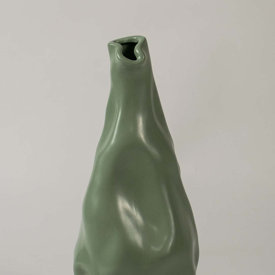 Closeup view of the green sculpted vase showing its smooth artistic contours and fluid handcrafted detailing that create a striking modern decorative accent for interiors.