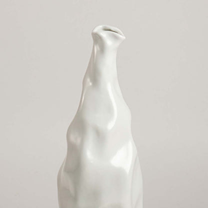 Closeup view of a sculpted white ceramic vase showing its textured organic surface and artistic curves in a clean minimal composition.
