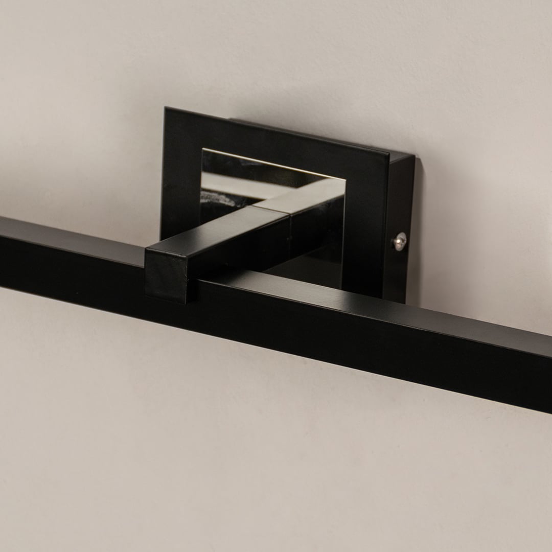 Closeup of black metal picture light showing smooth finish and detailing with warm directional illumination.