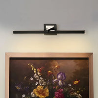 Closeup lifestyle view of black metal picture light on a styled wall adding warm focused accent lighting.