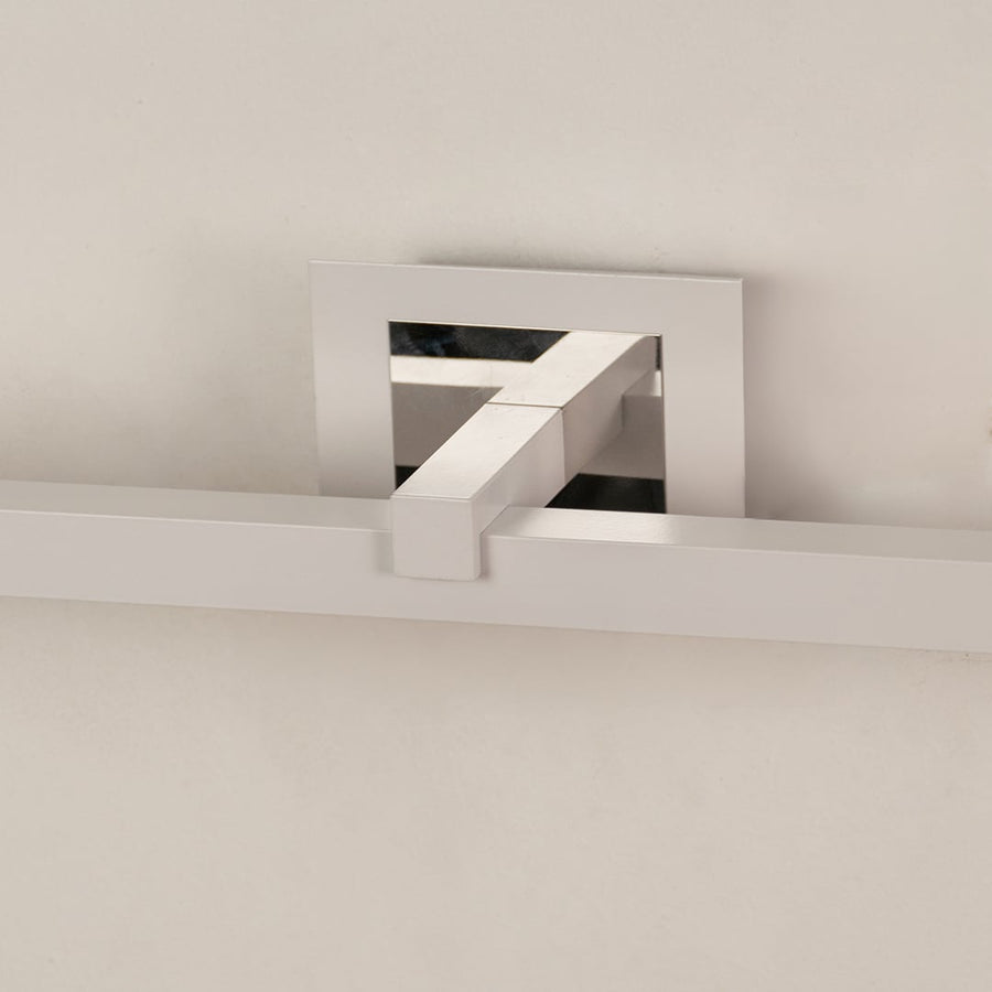 Closeup of silver metal picture light showing smooth finish and detailing with warm focused illumination.