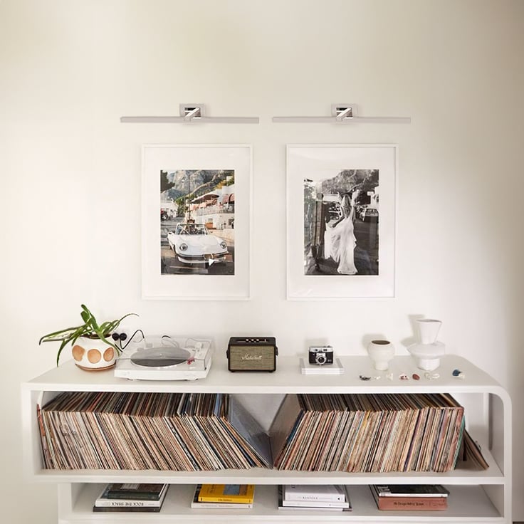 Silver metal picture lights styled together on a modern wall creating balanced warm illumination for home decor.