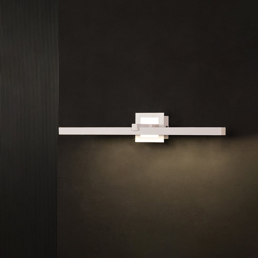 Silver metal picture light glowing warmly on a black background creating a bold modern wall lighting effect.