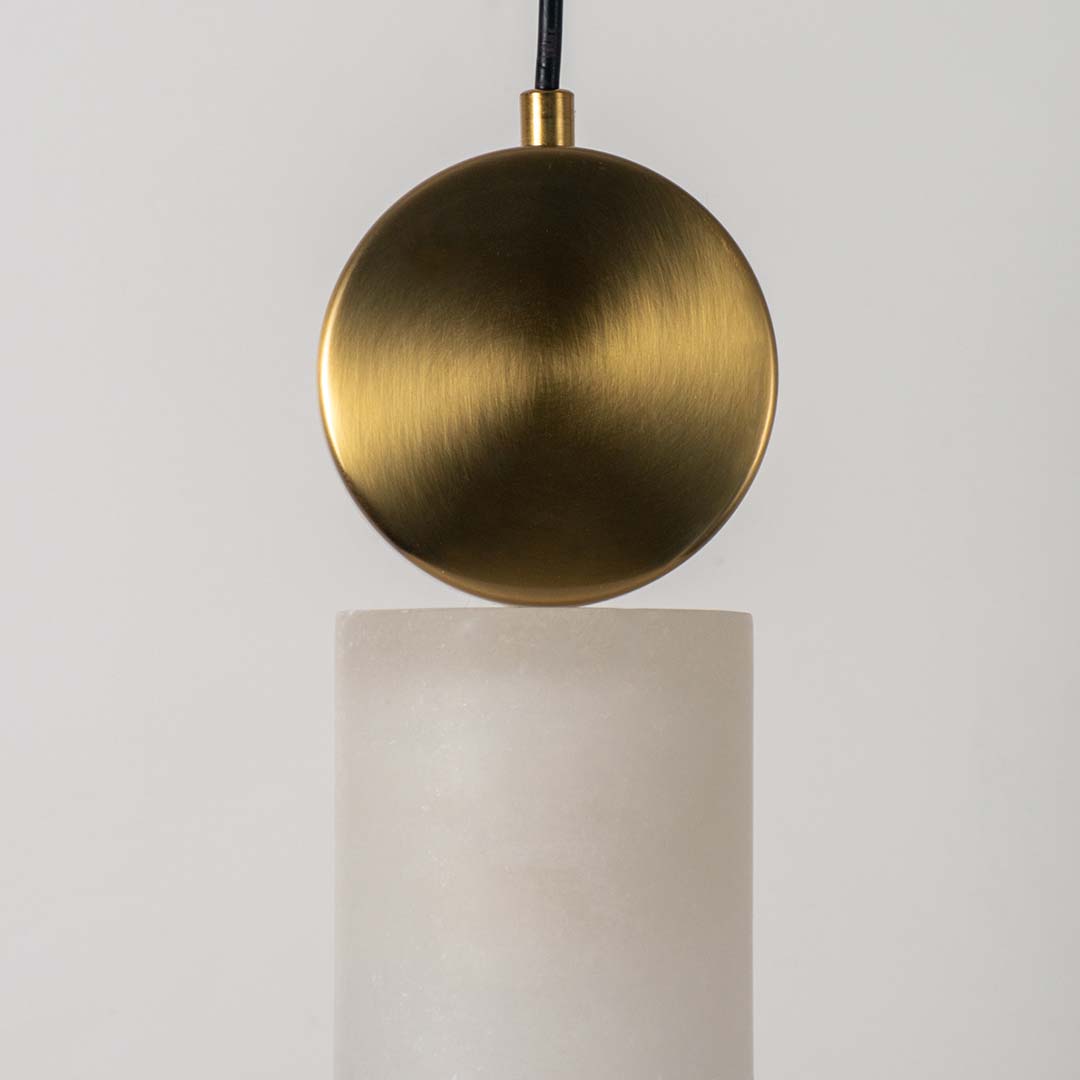 Closeup of modern gold pendant lamp with frosted cylindrical glass shade highlighting luxury finish and elegant design.