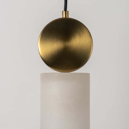 Closeup of modern gold pendant lamp with frosted cylindrical glass shade highlighting luxury finish and elegant design.