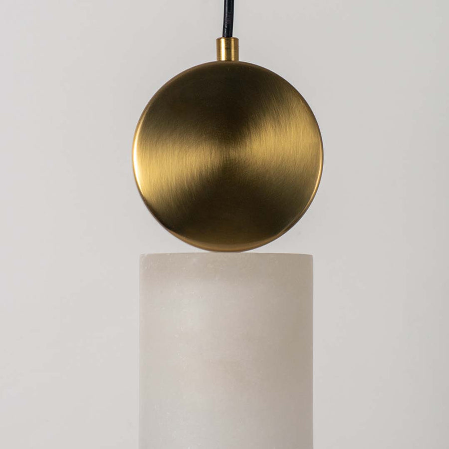Closeup of modern gold pendant lamp with frosted cylindrical glass shade highlighting luxury finish and elegant design.