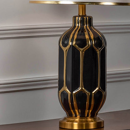 Closeup of black and gold ceramic table lamp base showing geometric ribbed form glossy finish and luxury decorative detailing.