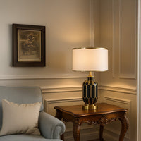 Elegant black gold ceramic lamp with white shade styled on a wooden side table in a classic living room.
