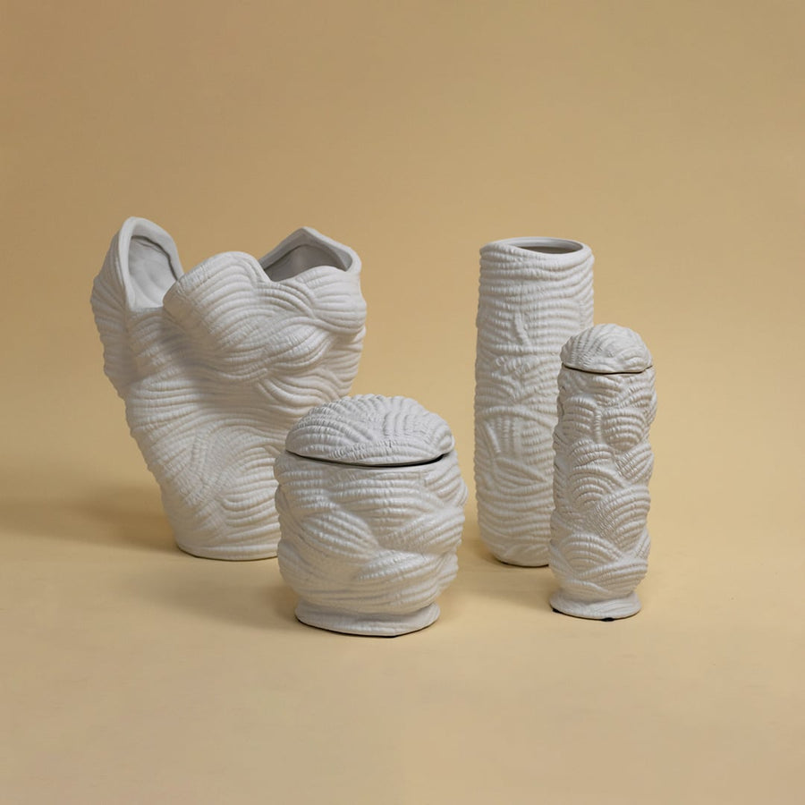 Set of white textured ceramic vases arranged together under soft lighting creating a modern art-inspired decorative ensemble.