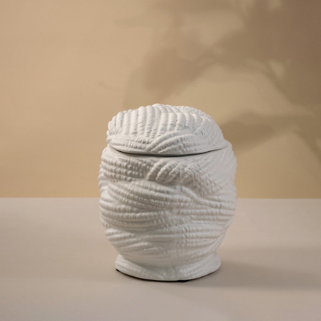 Handcrafted white ceramic vase with a textured pattern glowing gently under light on white background showing artistic craftsmanship.