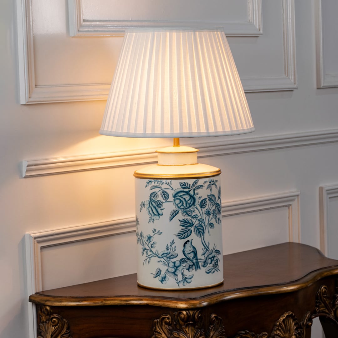 White ceramic table lamp with blue floral pattern and pleated fabric shade for elegant bedside lighting decor.