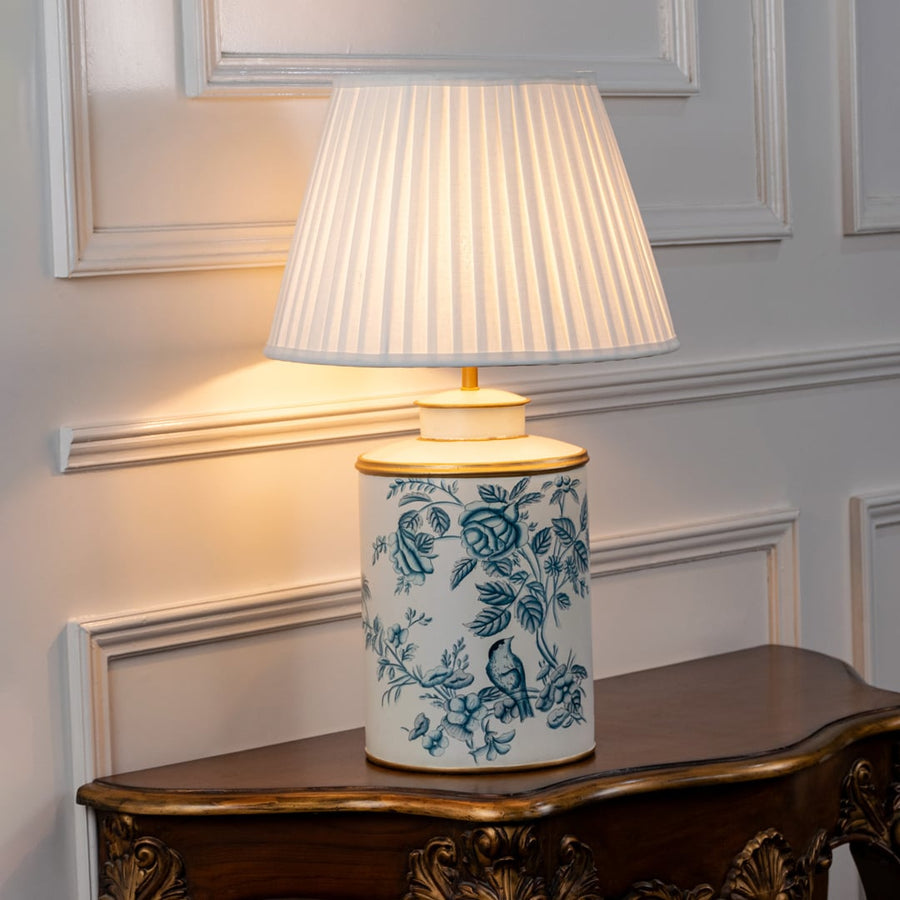 White ceramic table lamp with blue floral pattern and pleated fabric shade for elegant bedside lighting decor.