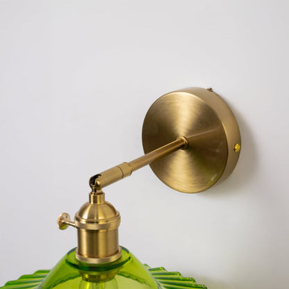 Closeup of gold metal wall light with green glass shade for luxury ambient lighting decor styling ideas.