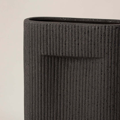 Closeup view of black ceramic vase highlighting fine ribbed texture and matte finish ideal for tabletop home styling.
