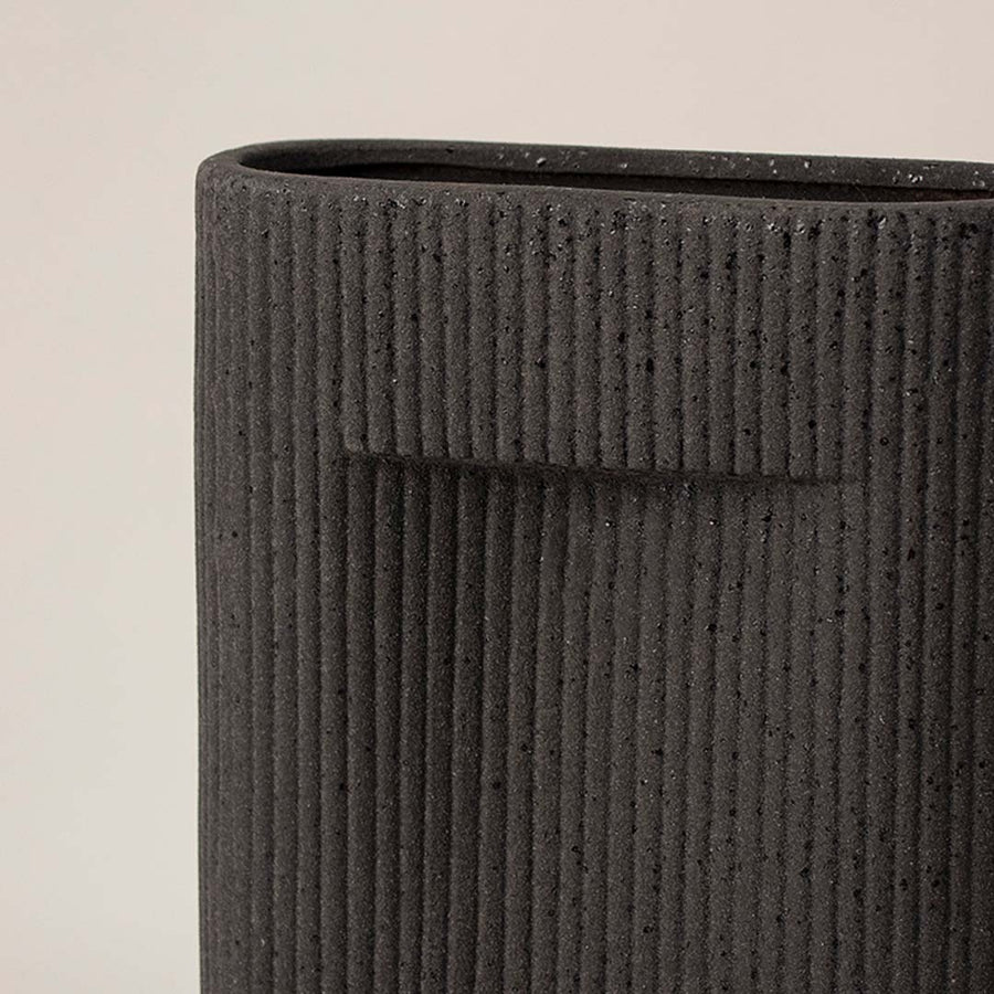 Closeup view of black ceramic vase highlighting fine ribbed texture and matte finish ideal for tabletop home styling.