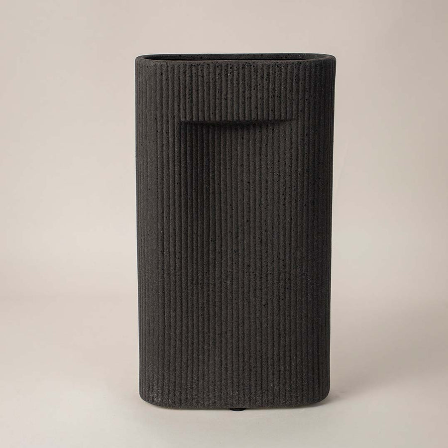 Black ribbed rectangular ceramic vase styled in modern interior setup ideal for elegant living room or office decoration.