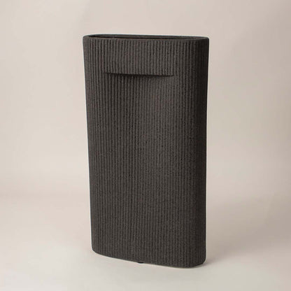 Ribbed black ceramic vase with soft matte finish placed side way showcasing its bold modern silhouette.