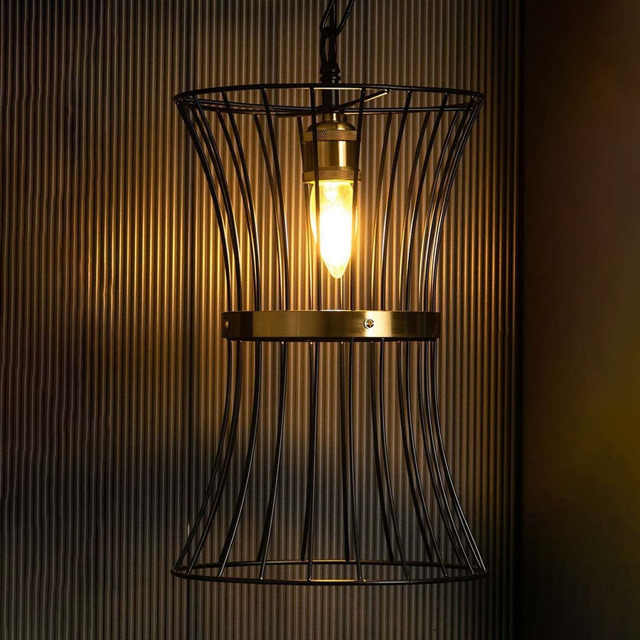 Black metal cage pendant illuminated warmly against a dark ribbed backdrop showcasing its curved frame brass ring and glowing bulb clearly.