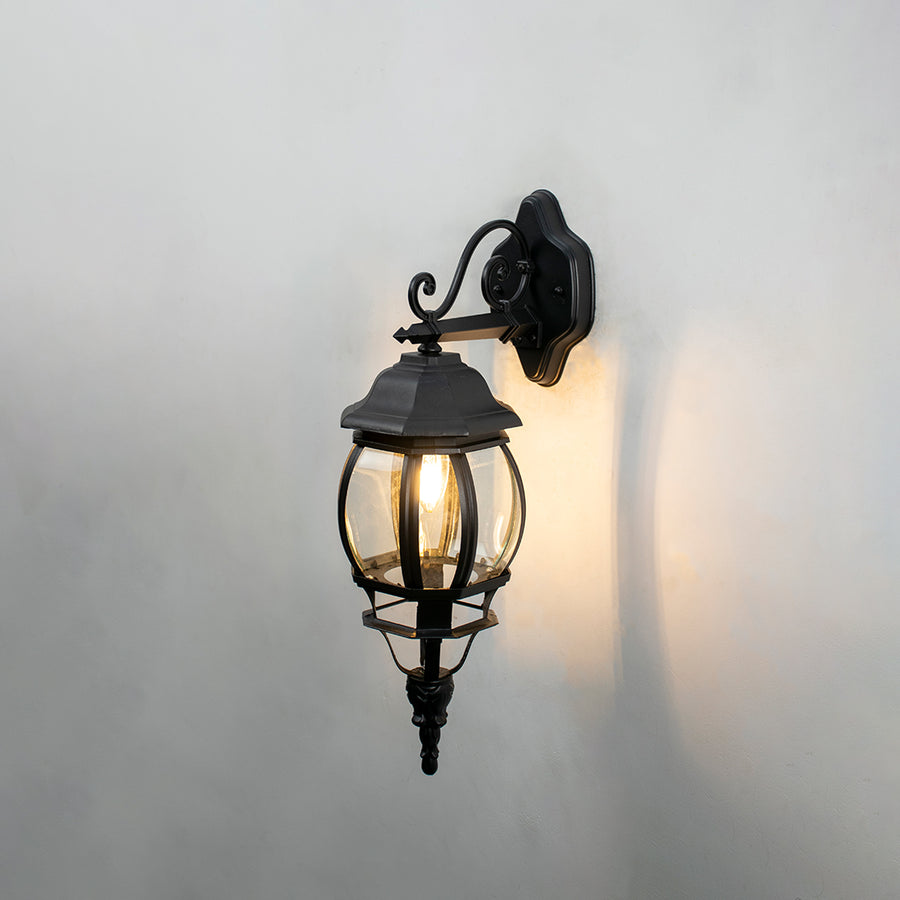 Black metal outdoor wall light on white background with warm ambient glow for classic exterior lighting decor.