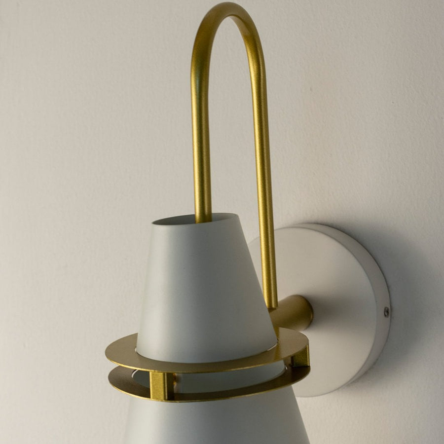 Closeup of modern wall light showing detailed brass structure and smooth white shade texture.