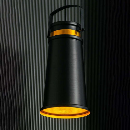 Black and gold pendant light on dark background with light on creating a focused warm beam through the golden reflector.