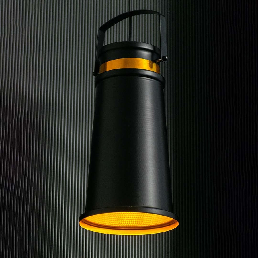 Black and gold pendant light on dark background with light on creating a focused warm beam through the golden reflector.