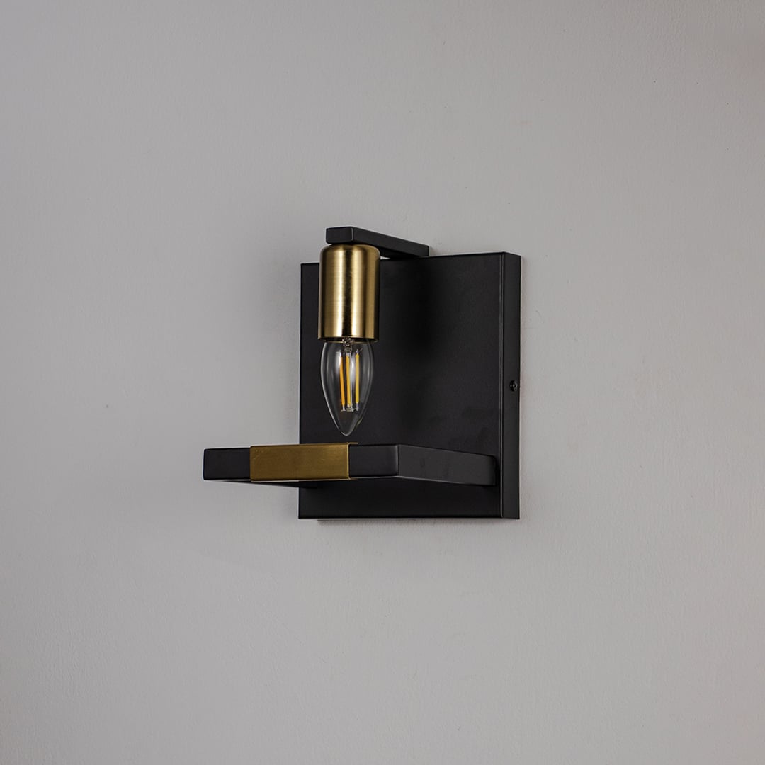 Black and gold wall light with metal frame and exposed bulb shown off on white background for modern interior wall decor.