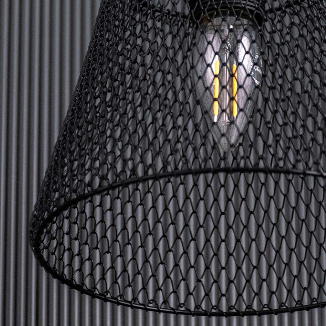Close detailed angle of the black mesh pendant revealing the tightly woven metal grid and warm filament bulb for a stylish industrial lighting effect.