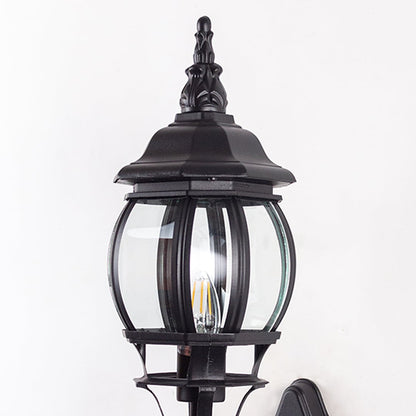 Closeup of black upward wall lantern showing curved glass cage scroll bracket detail and decorative finial vintage design.