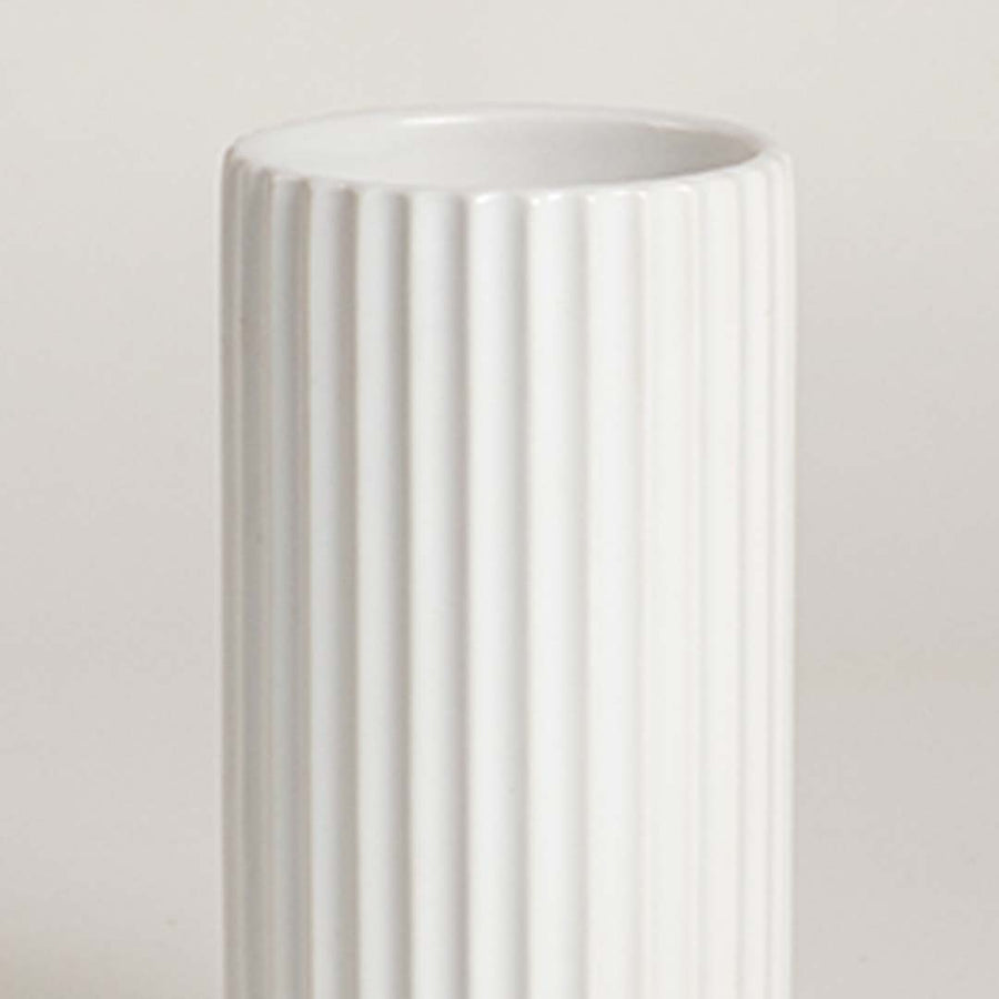 Closeup of white ceramic vase with vertical ribbed texture showcasing premium craftsmanship and modern decor styling.